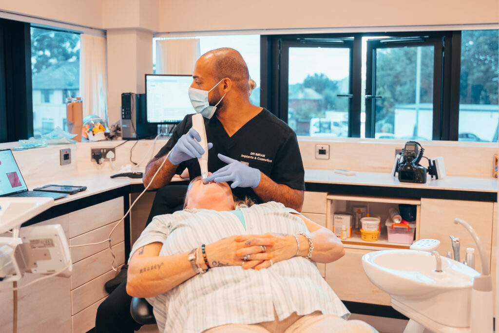 Dental clinic interior. Dental implant specialist using an intramural scanner with a patient.